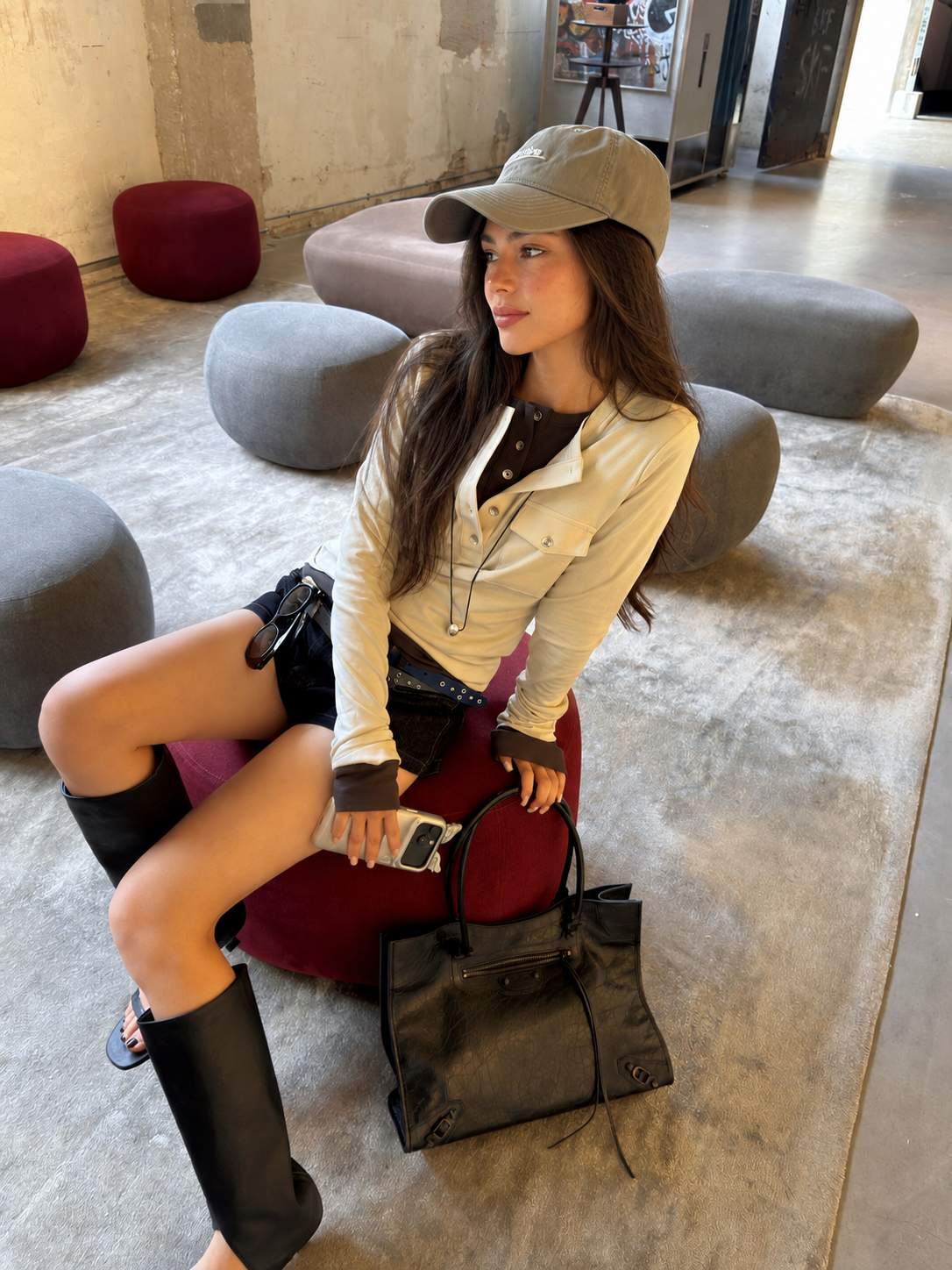 Model sitting in the Florise Studio Vintage Utility Henley Top in Ivory Cream, showcasing the button-front Henley neckline, utility chest pockets, and soft stretch cotton fabric.