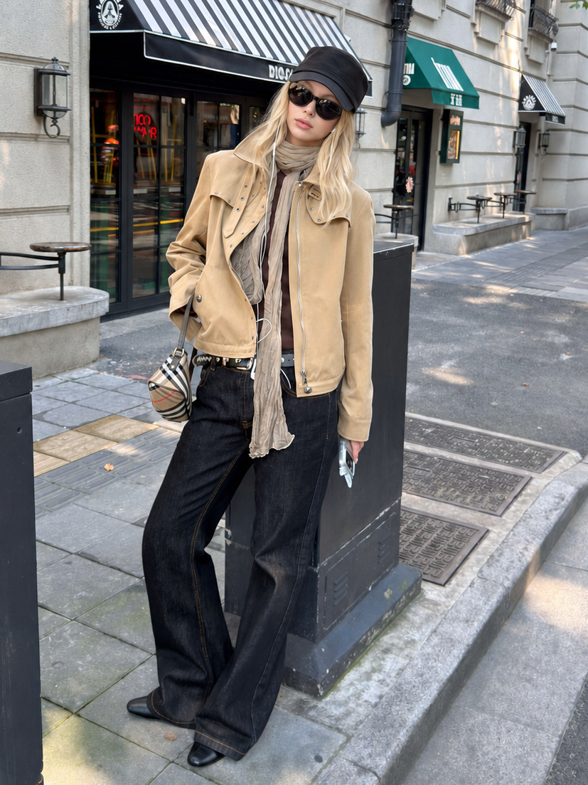 Woman wearing the Florise Studio Vintage Stud Utility Jacket in Desert Sand, styled with dark denim jeans, a lightweight scarf, and sunglasses for a modern vintage streetwear look.