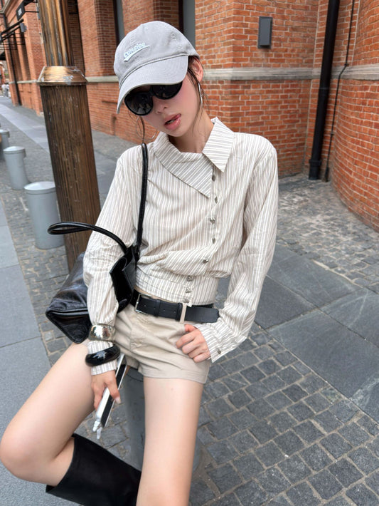 Close-up of an asymmetrical striped cotton blouse featuring diagonal buttons and gathered waist