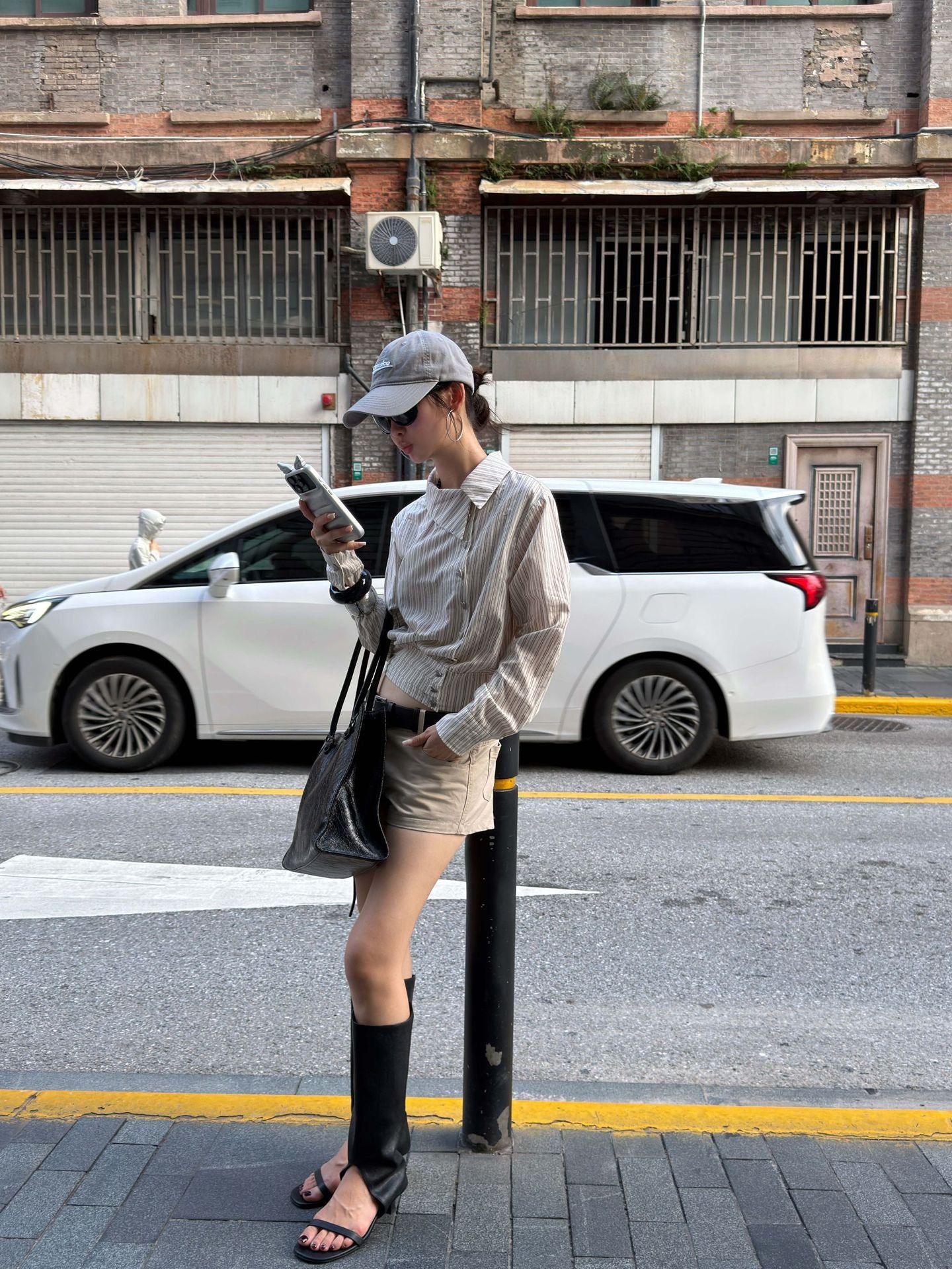 Street style outfit featuring an asymmetric striped cotton shirt paired with neutral shorts
