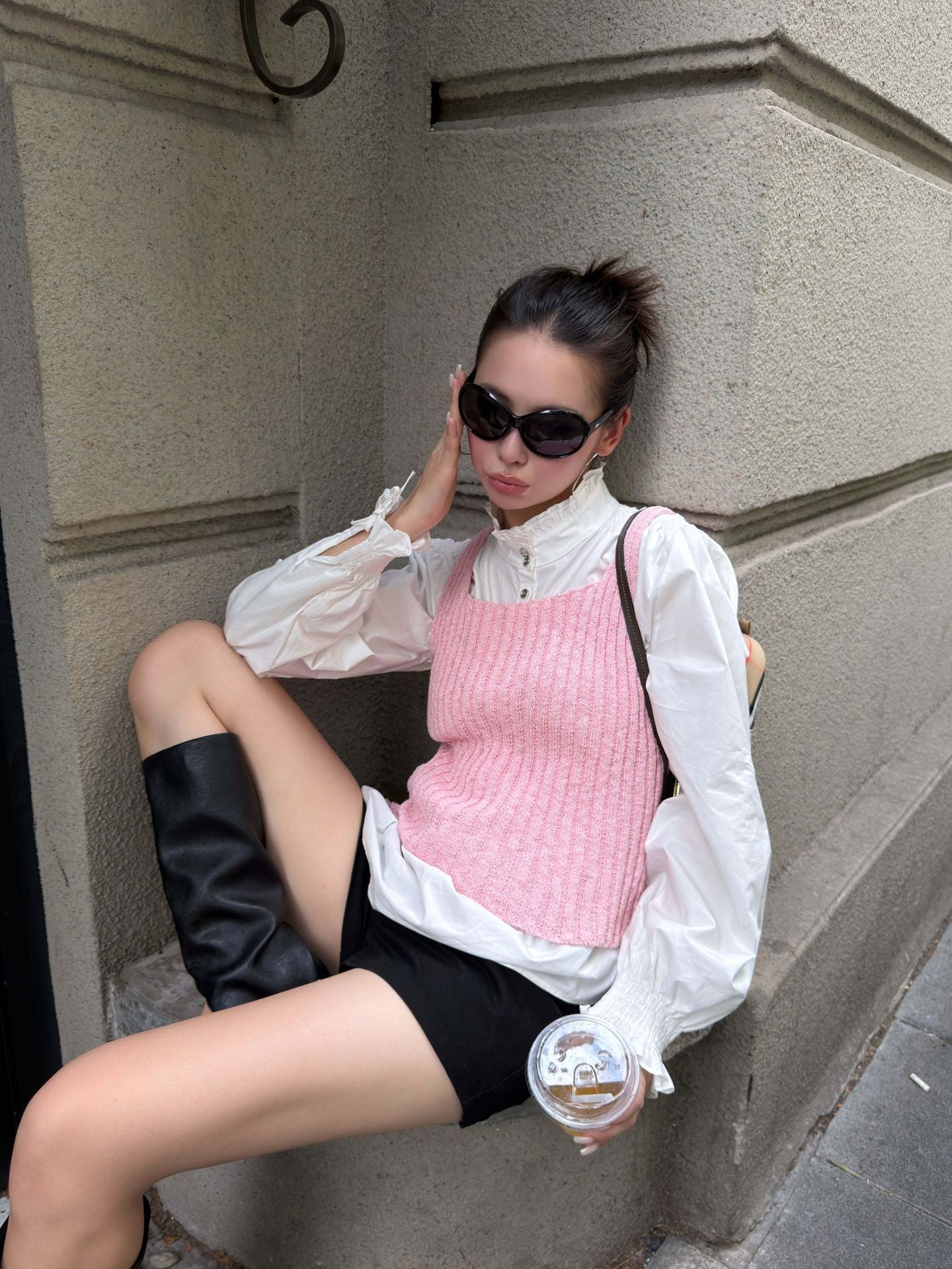 Blush pink ribbed knit sleeveless tank top layered over white shirt with knee high boots for chic city street fashion