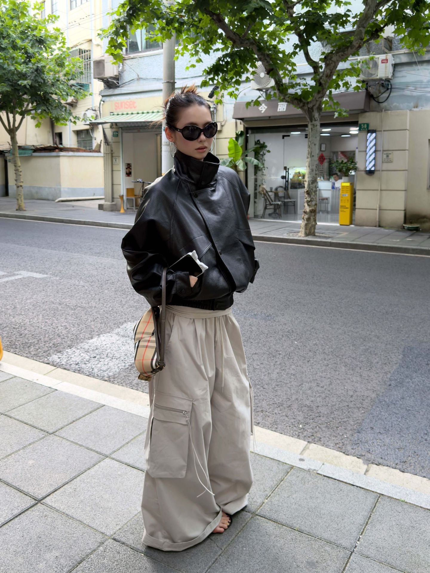 Model wearing Vintage Foldover Waist Wide Leg Cargo Pants in Stone Mist with an oversized black jacket on a city street.