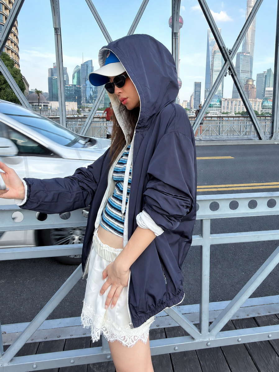 Side view of the Florise Studio Reversible Oversized Zip Hoodie Jacket reversed to Midnight Navy, featuring the smooth shell exterior, oversized hood, and lightweight wind-resistant finish.