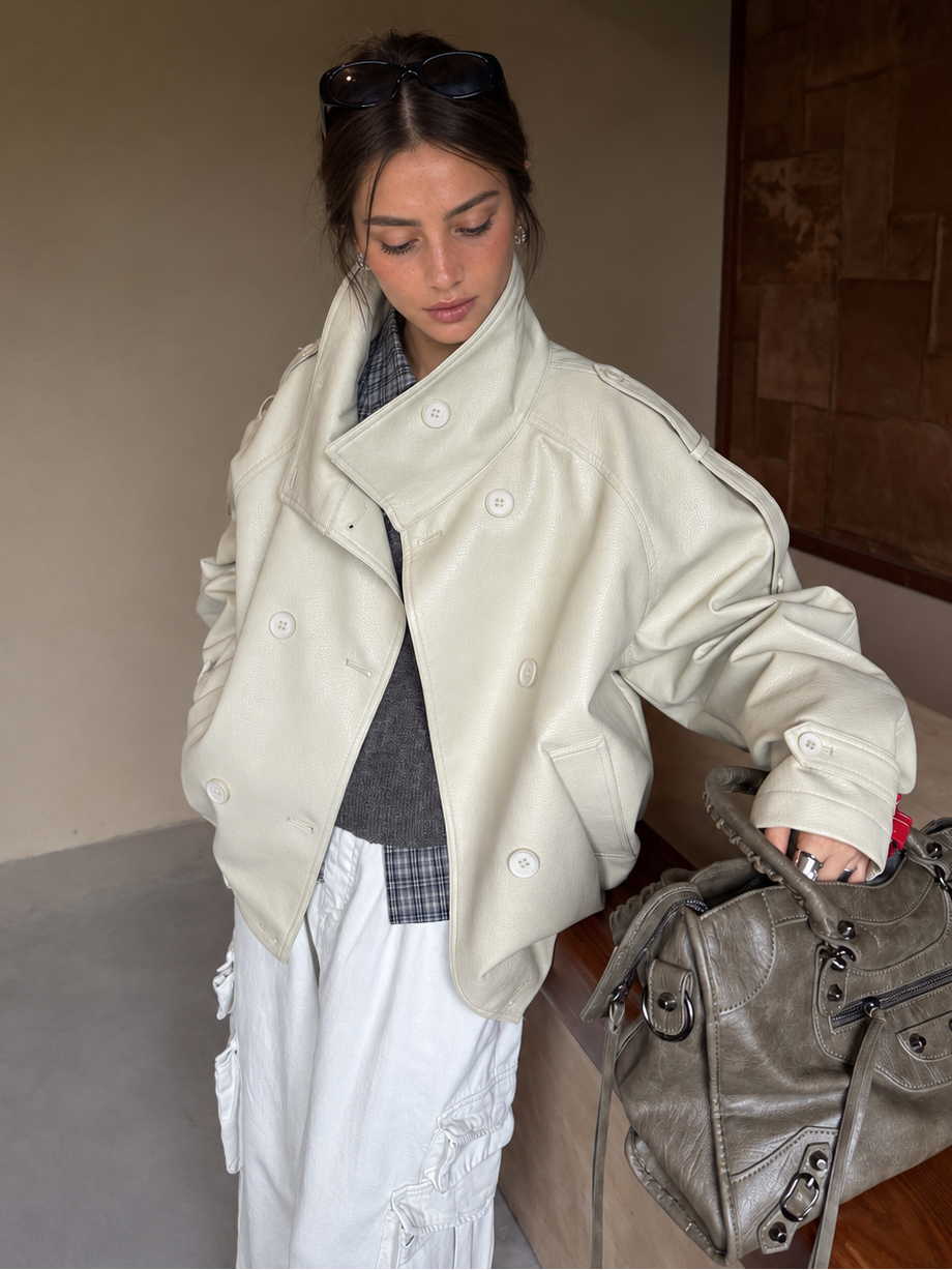 Woman wearing the Avery Oversized Faux Leather Moto Jacket in Soft Ivory styled with layered knitwear and a white cargo skirt.
