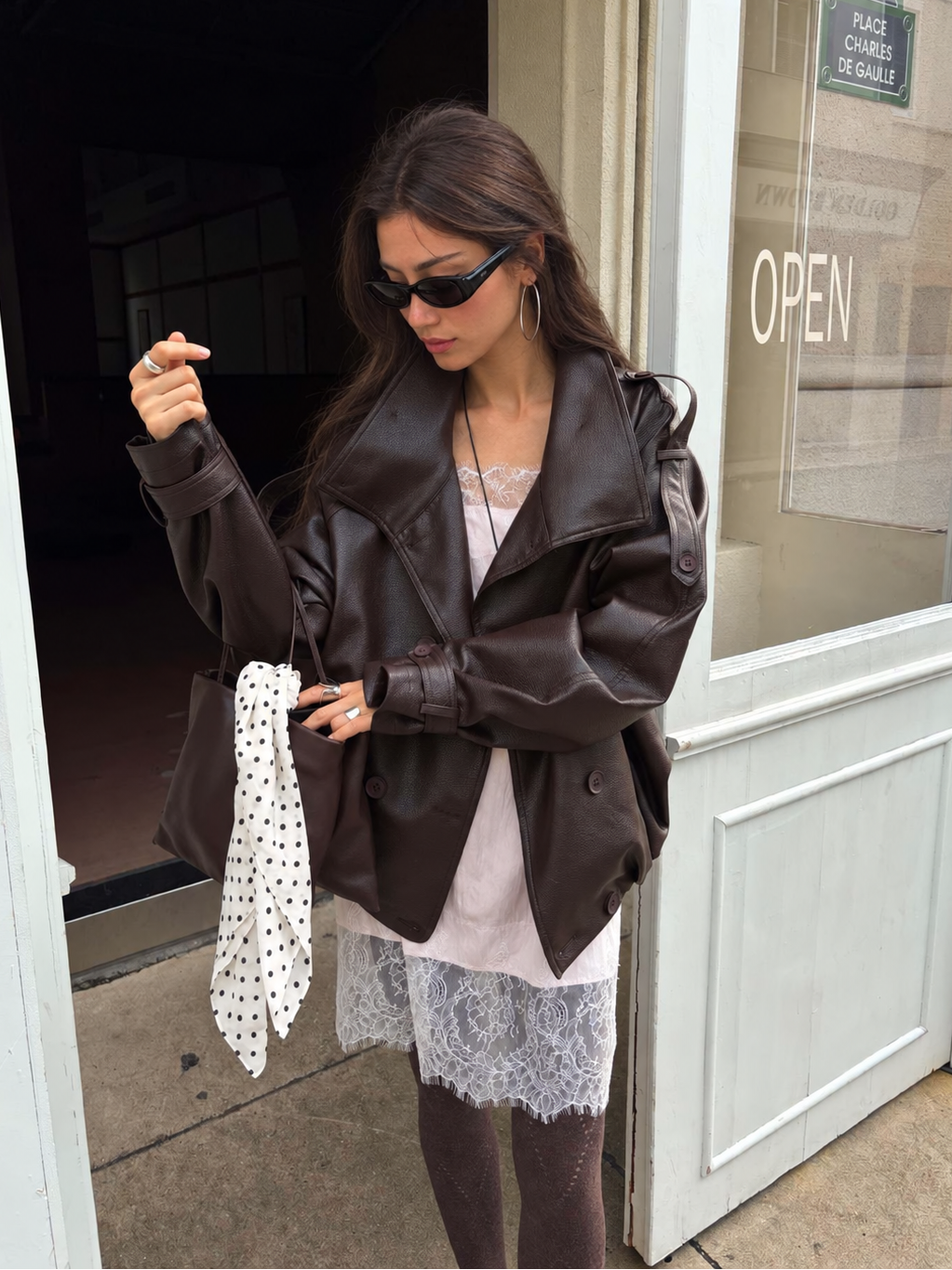 Model wearing the Celeste Lace Layering Slip Dress in Blush Pink beneath a dark brown leather jacket, featuring eyelash lace detailing and a relaxed silhouette.