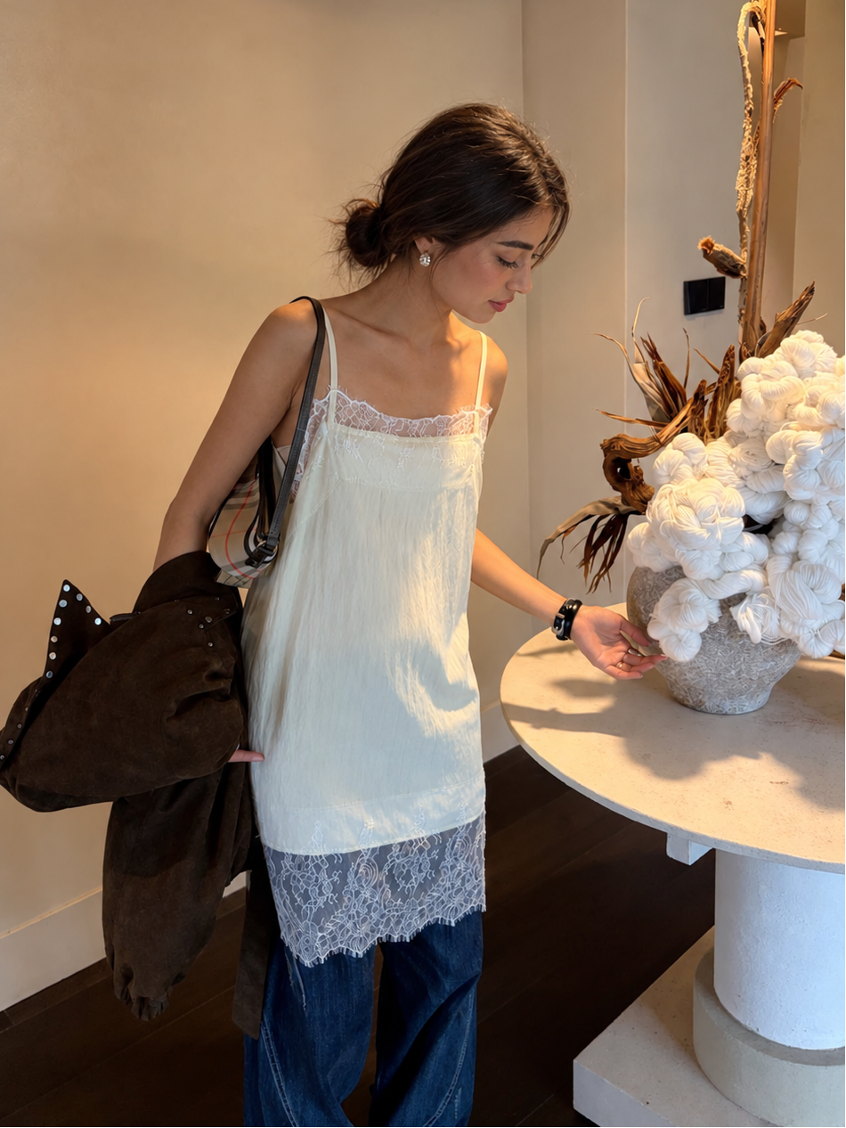 Model styling the Celeste Lace Layering Slip Dress in Soft Butter over relaxed blue jeans, highlighting the lightweight textured fabric and lace hem.