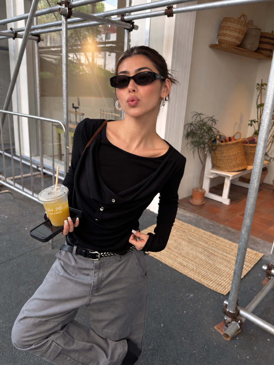 Side styling view of black draped button long-sleeve top